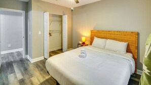 A hotel room with a bed, a ceiling fan, a nightstand with a lamp, and a door leading to a closet.