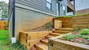 A residential area with a wooden staircase leading to a deck, surrounded by a wooden fence and a garden.