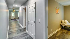 A hallway with a wooden floor, white doors, and a bench with pillows.