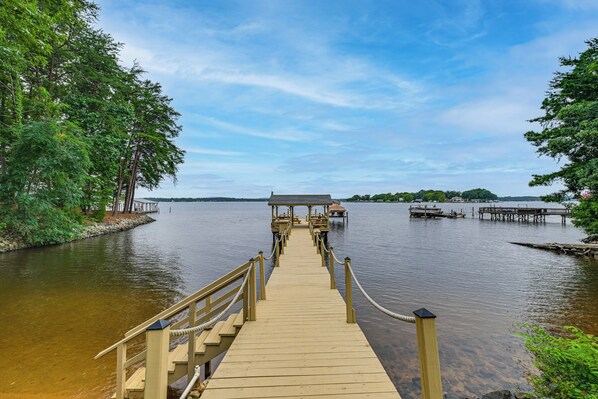 A wooden pier leading to a dock with a covered seating area. - 'sunset Central' - Lake Norman Getaway With Dock (Mooresville)