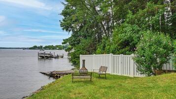 Une propriété au bord du lac, dotée d’un quai, d’une clôture blanche et d’un banc.