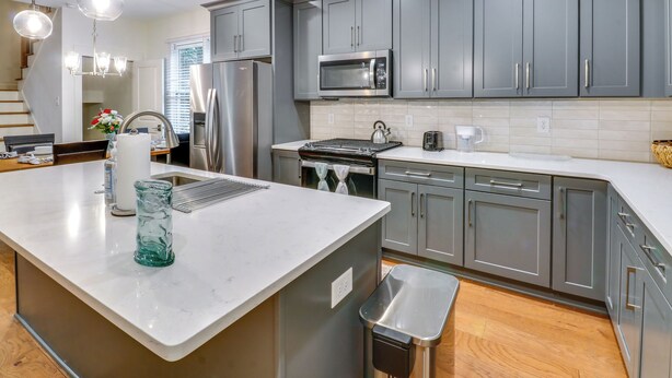 A modern kitchen with grey cabinets, stainless steel appliances, and a white countertop. - Easy I-20 Access: Family Escape w/ Deck in Decatur (Decatur)