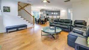 A spacious living area with a wooden staircase, a glass coffee table, leather sofas, and a kitchen in the background. - Easy I-20 Access: Family Escape w/ Deck in Decatur (Decatur)