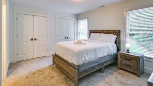 A bedroom with a bed, nightstand, and a window with blinds. - Easy I-20 Access: Family Escape w/ Deck in Decatur (Decatur)