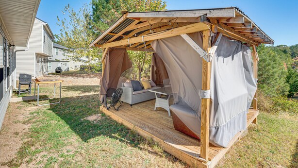 A wooden deck with a covered seating area, a grill, and a table.