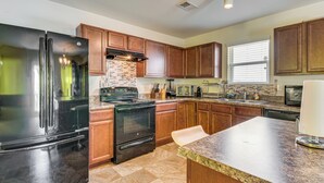 A modern kitchen with stainless steel appliances, wooden cabinets, and a granite countertop.