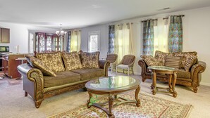 A living room with a sofa, two armchairs, a coffee table, and a patterned rug.
