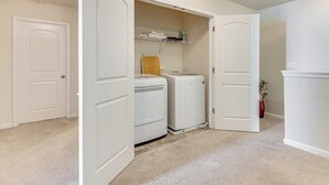 A laundry room with a washing machine, dryer, and a shelf with folded towels.