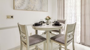 A dining area with a round table, two chairs, a vase with flowers, and a wall-mounted abstract painting. - Playground & Grill: Pet-friendly Griffin Getaway! (Griffin)