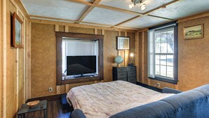 Une chambre à coucher avec un grand lit, une télévision, un globe terrestre et une fenêtre avec des stores.