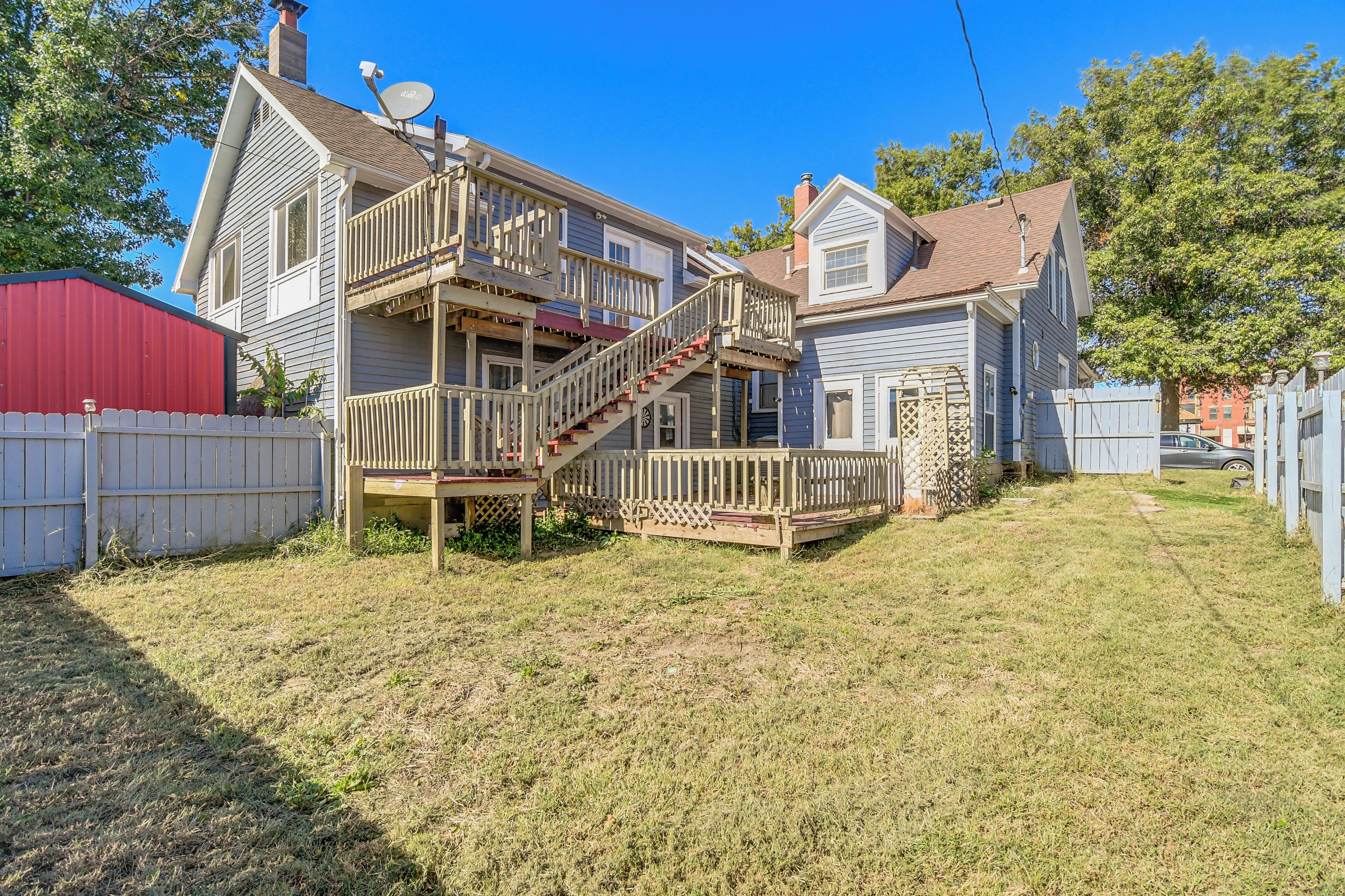 A two-story house with a wooden deck and a staircase leading to the second floor.