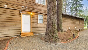 A wooden cabin with a white door, a small porch, and a gravel driveway. - 3 Acres! Spacious Waterfront Home in Amboy (Amboy)