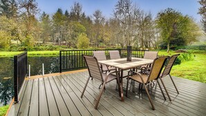 A wooden deck with a table and chairs overlooking a pond and trees. - 3 Acres! Spacious Waterfront Home in Amboy (Amboy)