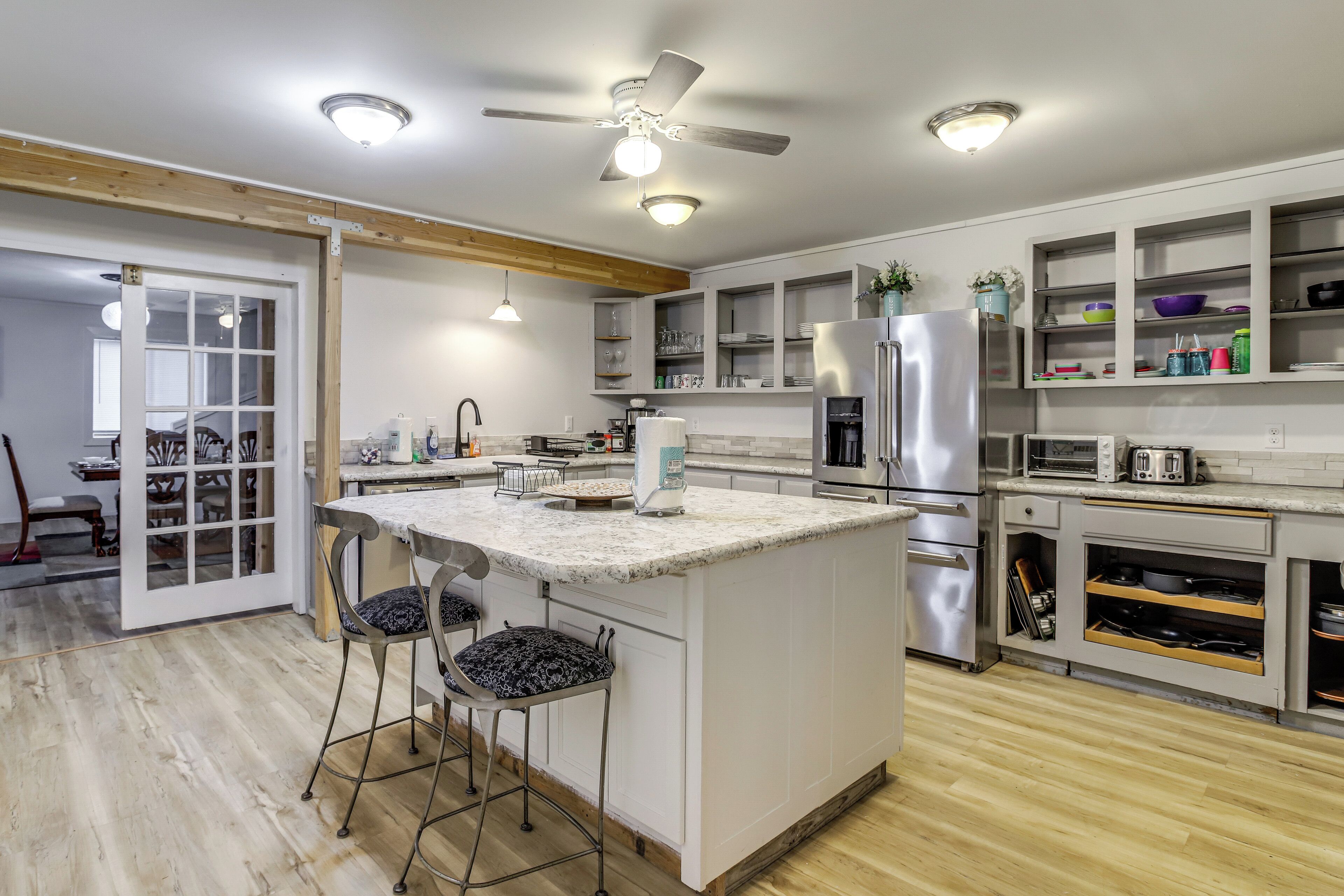 Una cocina moderna con una isla central, taburetes de bar, armarios empotrados y un ventilador de techo.