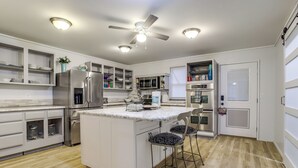 A modern kitchen with white cabinetry, stainless steel appliances, a marble island, and bar stools. - 3 Acres! Spacious Waterfront Home in Amboy (Amboy)