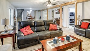 A spacious living room with a leather sofa, a wooden coffee table, and a ceiling fan. - 3 Acres! Spacious Waterfront Home in Amboy (Amboy)
