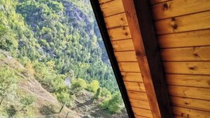 A wooden balcony with a view of a green valley and forested hills. - Bujtina Tinari (Theth)