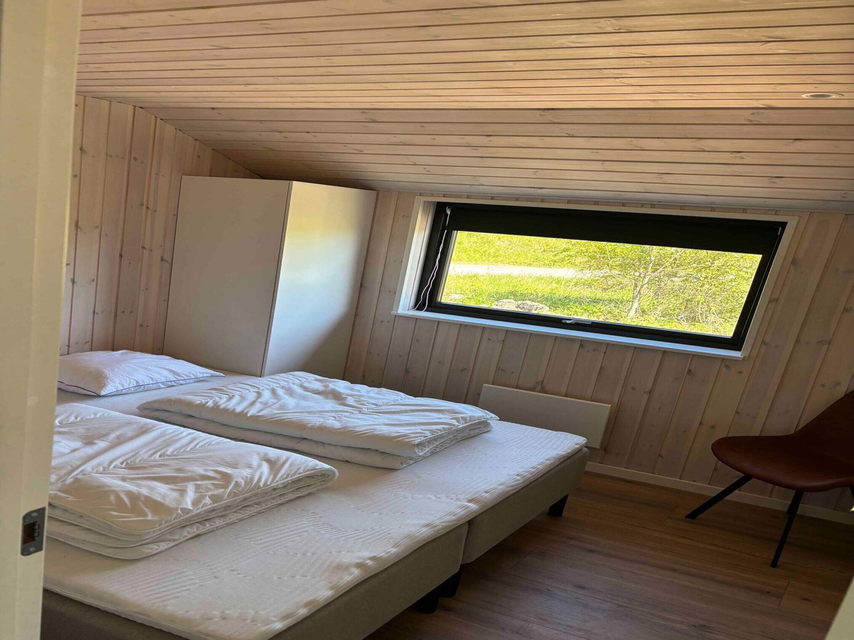 Un dormitorio con dos camas, una ventana que da a zonas verdes y un techo de madera.
