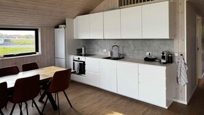 A modern kitchen with white cabinets, a built-in oven, and a window overlooking a grassy area. - 5 Star Holiday Home in Vaeggerlose (Vaeggerlose)