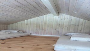 A small, wooden-paneled attic bedroom with two single beds and a wooden floor. - 5 Star Holiday Home in Vaeggerlose (Vaeggerlose)