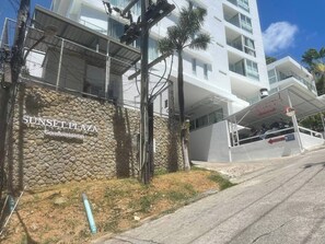 A modern building with a stone facade and a sign reading "Sunset Plaza Condominium." - B11 Sunset Plaza Partial Seaview 1 Bedroom 1 Bathroom With Large Jaguzzi (Karon)