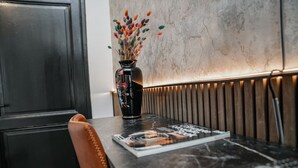 Ein Tisch mit einer Zeitschrift, einer Vase mit Trockenblumen und einer modernen Wand mit strukturierter Oberfläche.