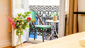 Ein Balkon mit Korbstuhl, Tisch und einer Topfpflanze.