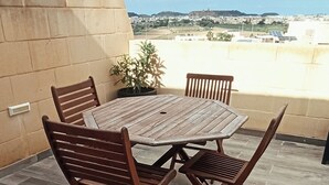 A round wooden table with four chairs on a tiled patio. - Near to Victoria. Cozy 2 bedroms penthouse with Citadel view. (Ta' Sannat)