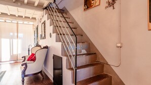 Un escalier avec une rampe, une chaise avec un coussin rouge et une porte.