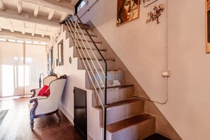 A staircase with a handrail, a chair with a red cushion, and a door.