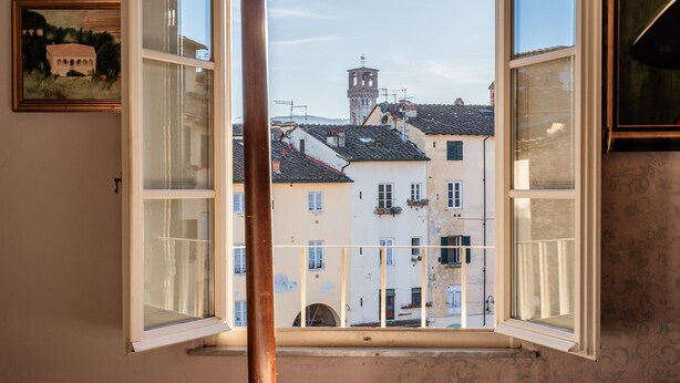 Une pièce avec une grande fenêtre, un lit et un tableau encadré au mur.