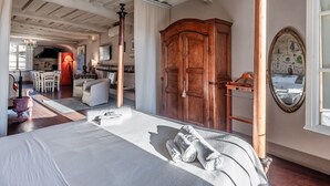Une chambre avec un lit, une armoire en bois, un miroir et une vue sur la cuisine.