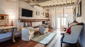 Un salon avec un plafond en bois, un téléviseur, des tableaux encadrés et un canapé.