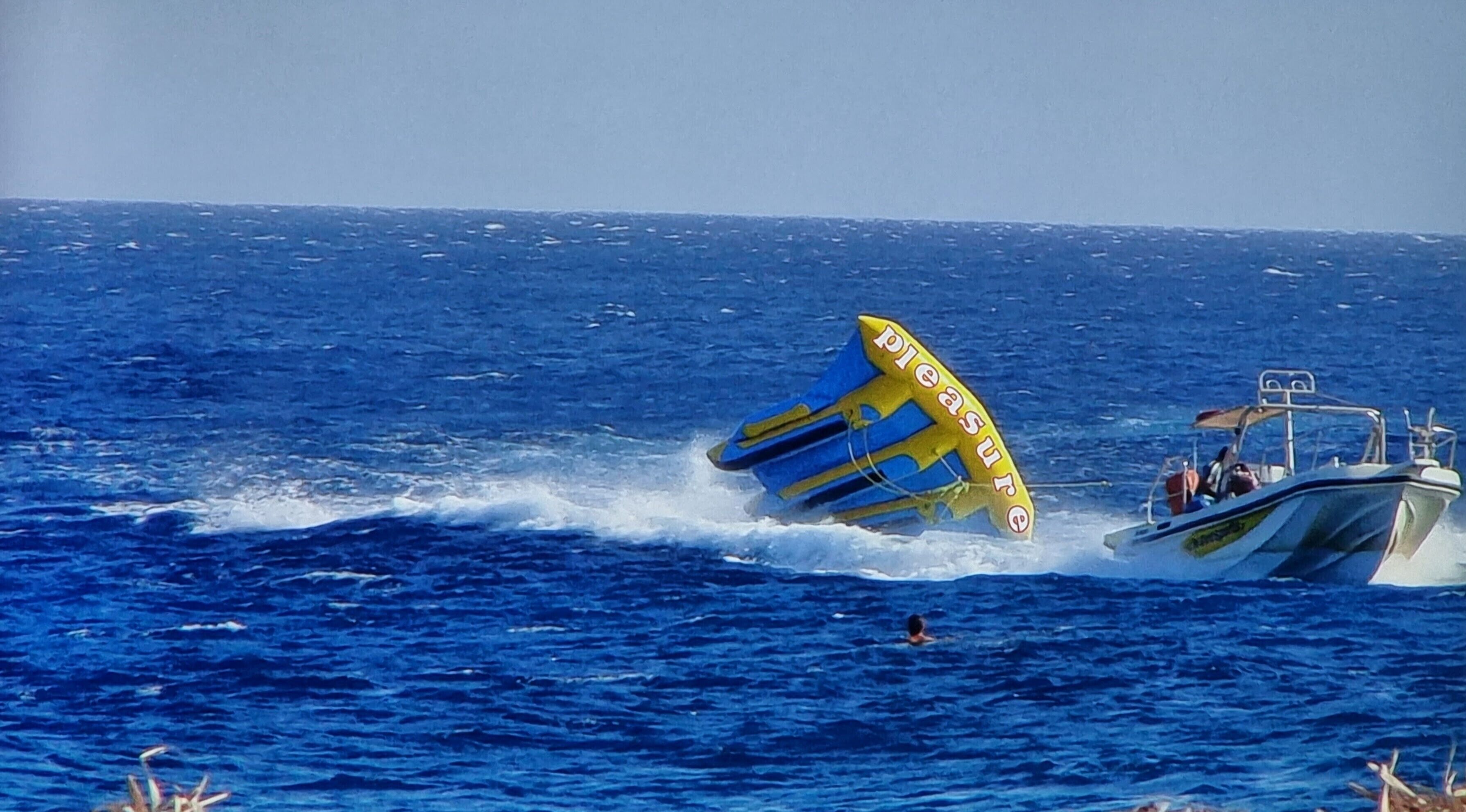 A boat with a yellow and blue sail in the ocean.