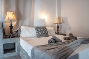 Une chambre d’hôtel comprenant un lit, deux lampes de chevet, un luminaire fixé au mur et une table de chevet.