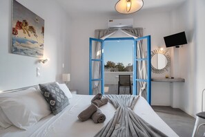 Ein Schlafzimmer mit Bett, einem Gemälde, einem Fernseher und Blick ins Freie.