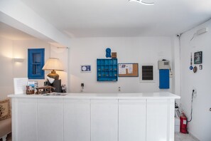 A reception desk with a lamp, a bulletin board, a blue shelf, and a fire extinguisher.