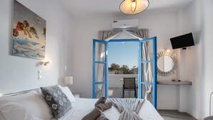 Une chambre à coucher avec un lit, un tableau, une télévision et une vue sur l’extérieur.