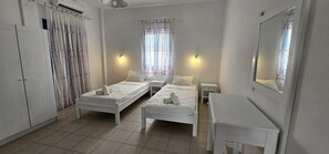 Una habitación con dos camas, un escritorio, un espejo y un armario.