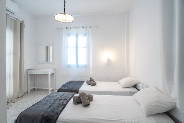 Une chambre dâhĂŽtel avec deux lits, un petit bureau, un miroir et une fenĂȘtre avec des rideaux.