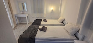 Ein Schlafzimmer mit zwei Betten, einem Nachttisch, einem Spiegel und einer Wandleuchte.