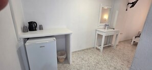 A small, clean bathroom with a white sink, mirror, and a refrigerator. - Economy Double Room 3 with Balcony and Air Conditioning (Perissa)