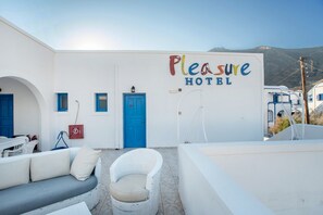A white building with a blue door, a blue chair, and a sofa.