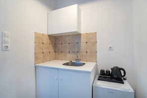 A small kitchenette with a sink, a kettle, and a coffee maker on a countertop.