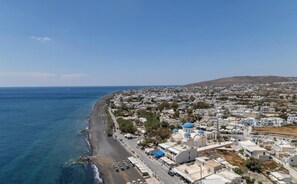A coastal town with a beach, buildings, and a hill in the background.