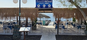 Ein Restaurant am Strand mit Außenbereich, einem Schild für South Wind und Blick aufs Meer.