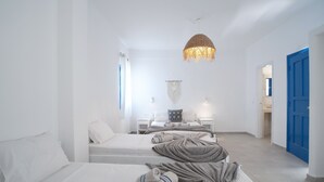 A hotel room with two beds, a blue door, and a hanging light fixture. - Economy Quadruple Room 5 with Mountain View, Balcony, and Air Conditioning (Perissa)