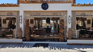 A restaurant with outdoor seating, a sign above the entrance, and a decorative ceiling. - Economy Quadruple Room 5 with Mountain View, Balcony, and Air Conditioning (Perissa)
