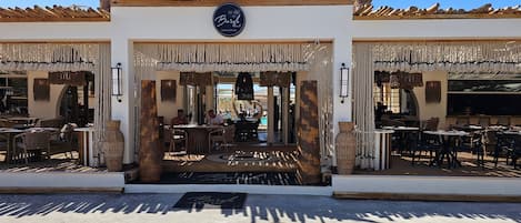 A restaurant with outdoor seating, a sign above the entrance, and a decorative ceiling.