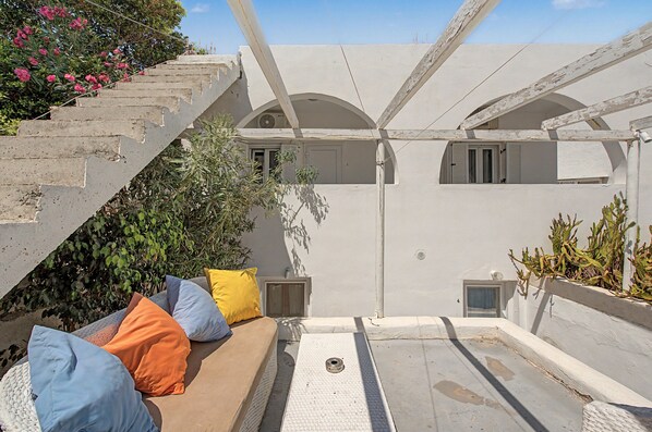 Une terrasse sur le toit aménagée avec un canapé, des coussins et des plantes en pot.